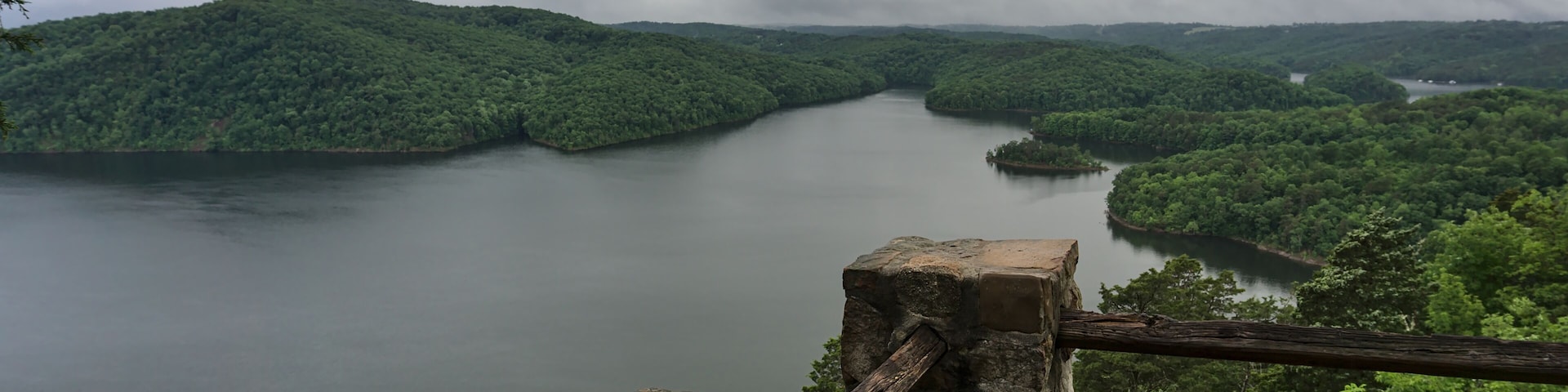 A river winding through a forested valley with a stone structure in the foreground.