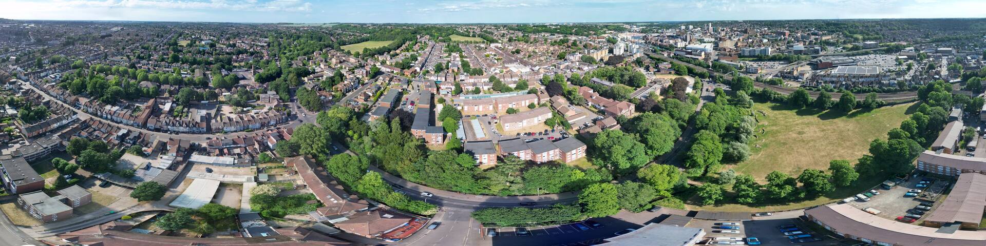 A panoramic view of a city with a central roundabout, surrounded by residential areas and commercial buildings.
