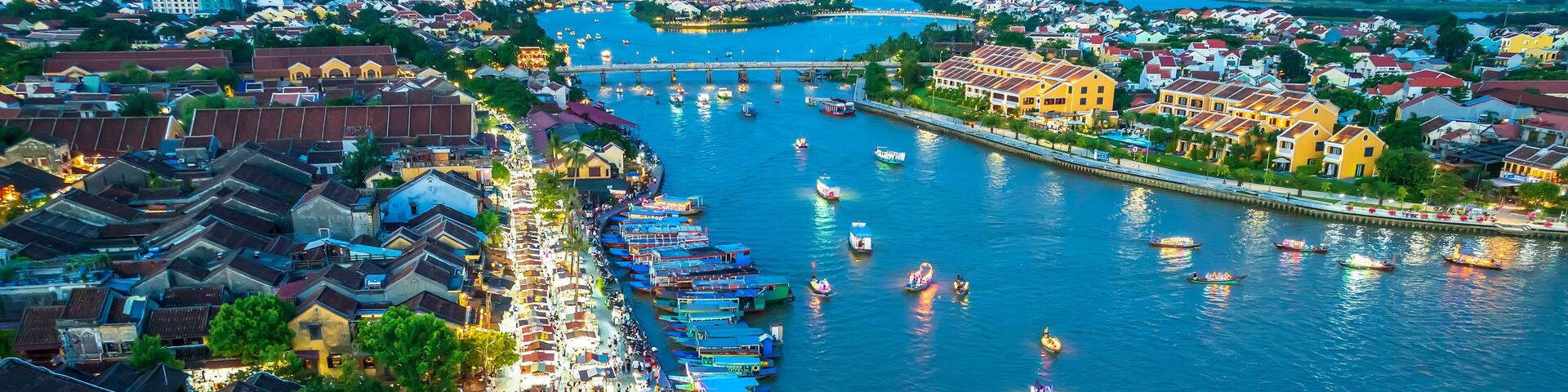 A bustling riverside town with colorful boats and traditional buildings.