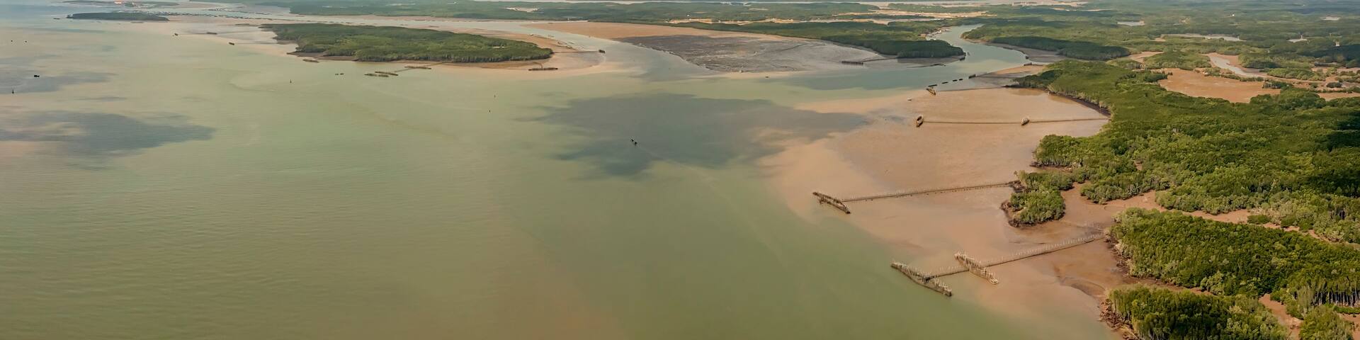 A coastal landscape with a river delta, sandy beaches, and dense greenery.