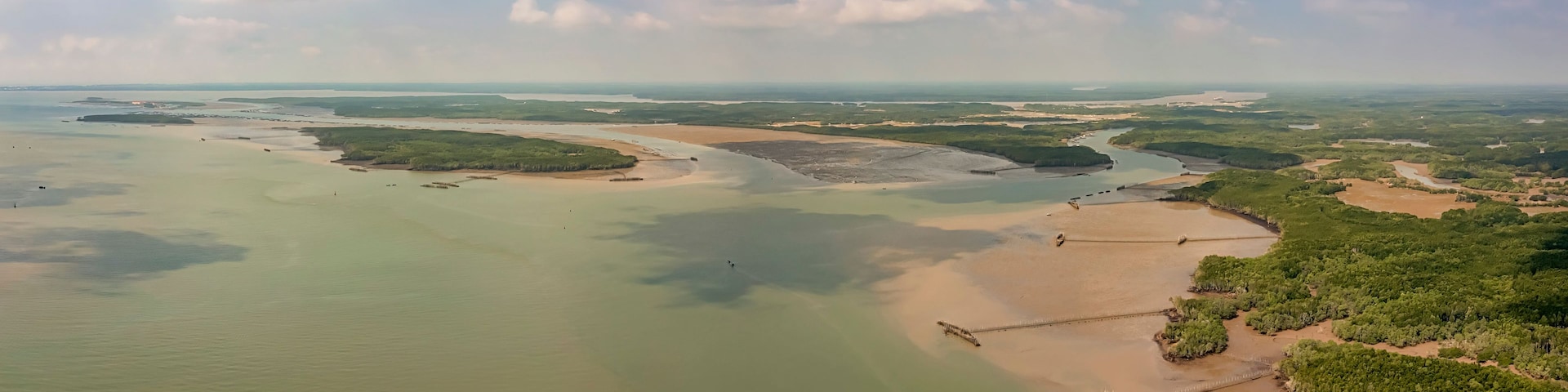 Et kystlandskab med en floddelta, sandstrande og frodig vegetation.