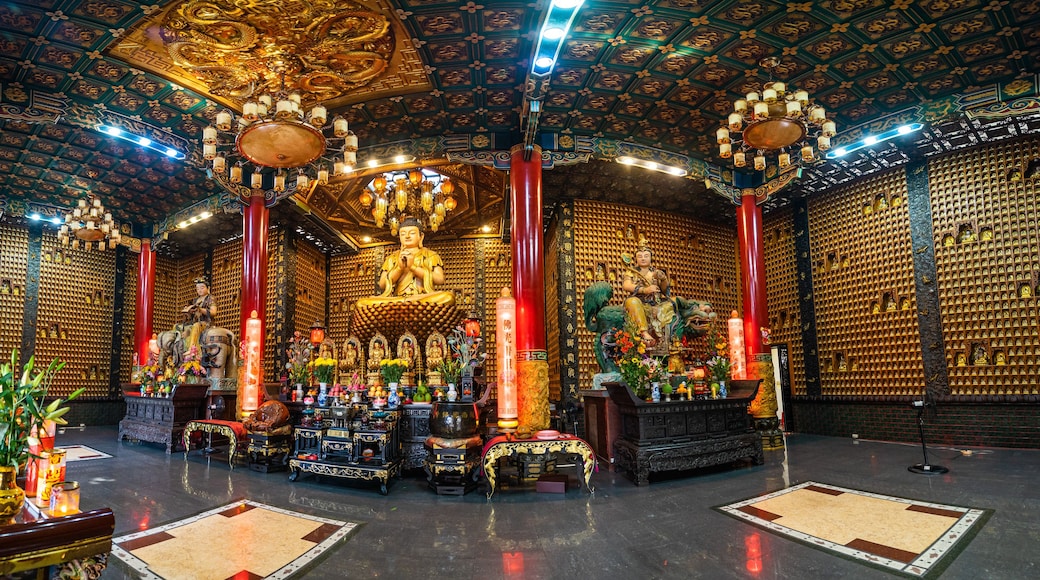 Et tempelinteriør med prangante gyldne udsmykninger, en stor Buddha-statue og traditionel kinesisk arkitektur.