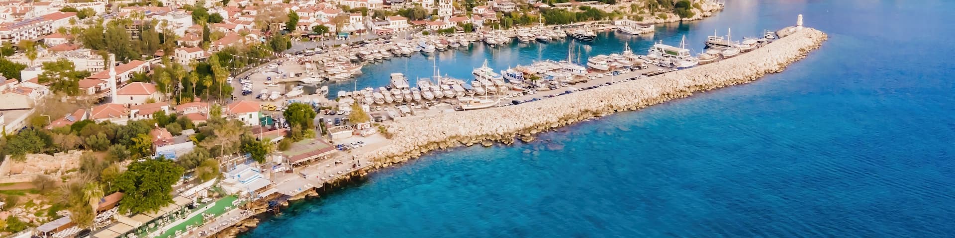 A coastal town with a marina, surrounded by mountains and clear blue waters.