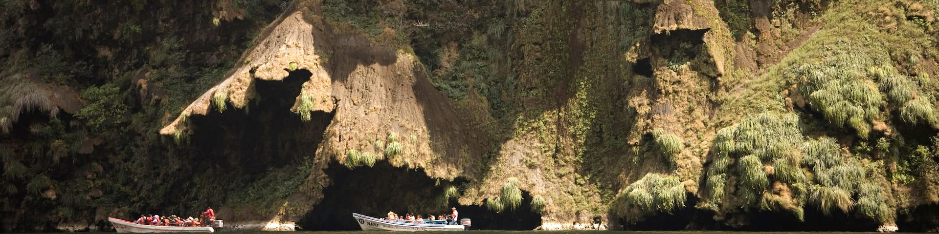 A boat on a river with a rocky cliff in the background.