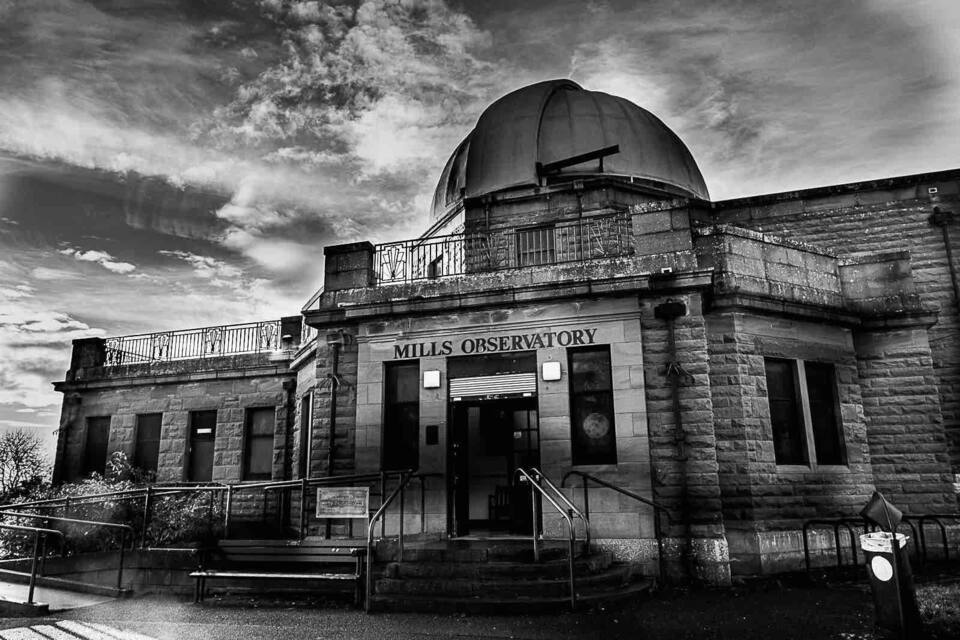 A historic observatory with a dome and a sign reading "Mills Observatory."