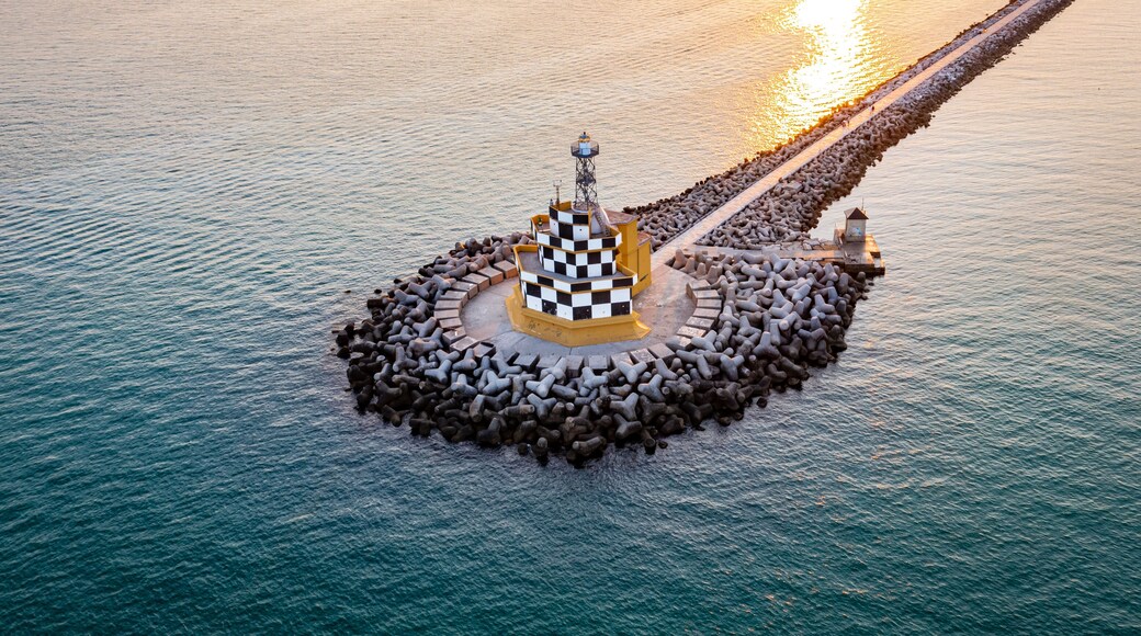 An aerial view of a lighthouse surrounded by a circular arrangement of rocks and a checkered structure.