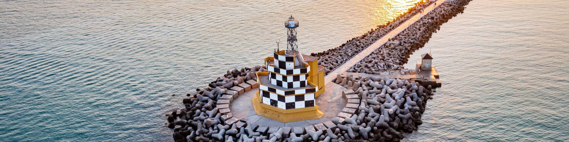An aerial view of a lighthouse surrounded by a circular arrangement of rocks and a checkered structure.