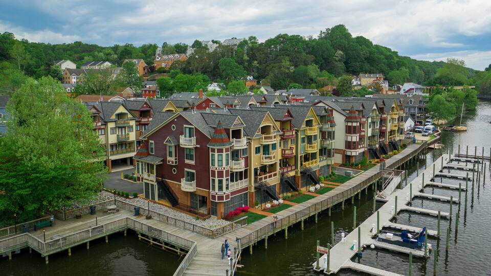 A waterfront row of colorful Victorian-style houses with a dock and boats.