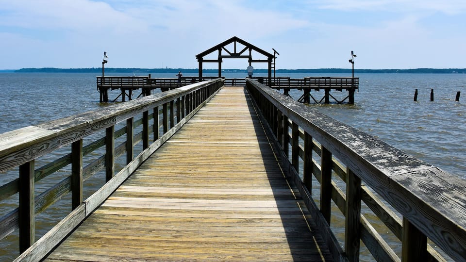 A wooden pier extending into a body of water with a small shelter at the end.