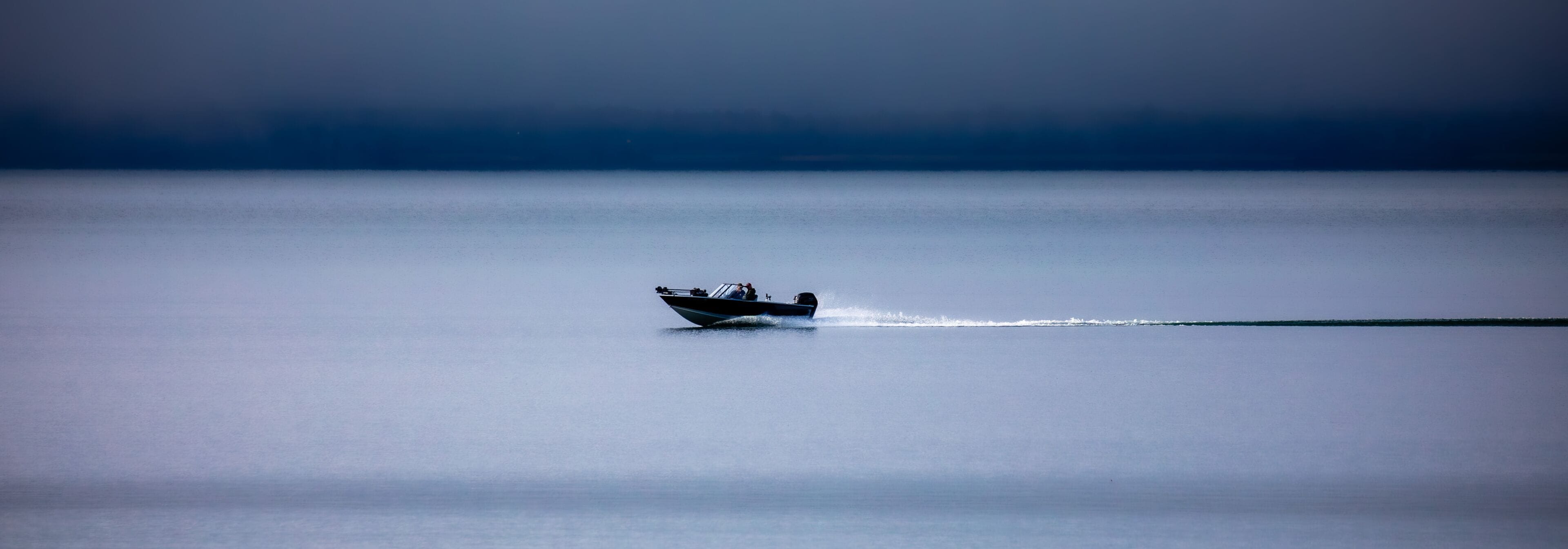 Two people in a fishing boat driving on Chequamegon Bay, on Lake Superior off of Washburn, Wisconsin in September