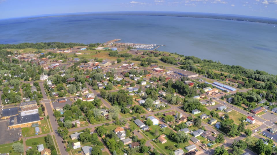 An aerial view of a coastal town with residential areas, a marina, and a large body of water.