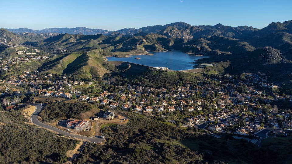 A coastal town nestled between mountains, with a bay and a winding road.