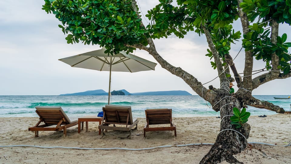 Beach chairs under a tree on the beach at the Longset Beach, Koh Rong, Cambodia