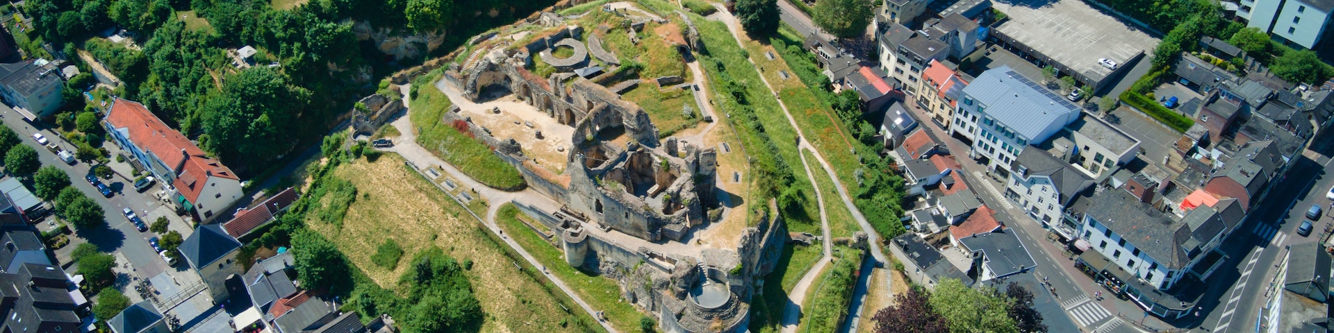 An aerial view of a historic site with ruins, surrounded by modern buildings and roads.