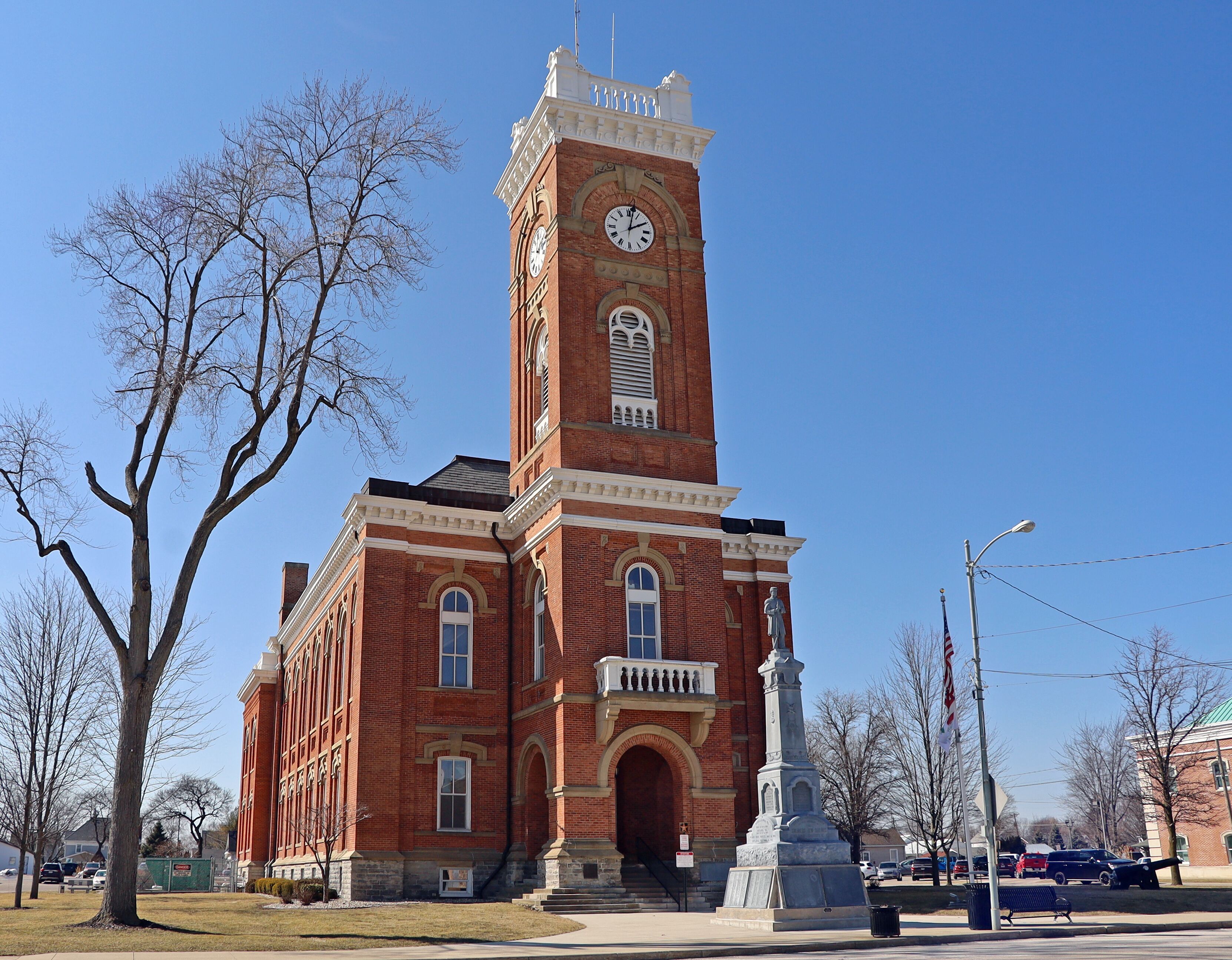 A red brick building with a clock tower and a statue in front.