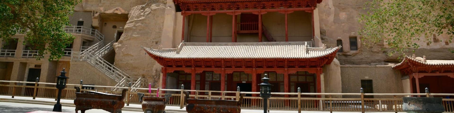 A traditional multi-tiered building with red accents, set against a rocky hillside.