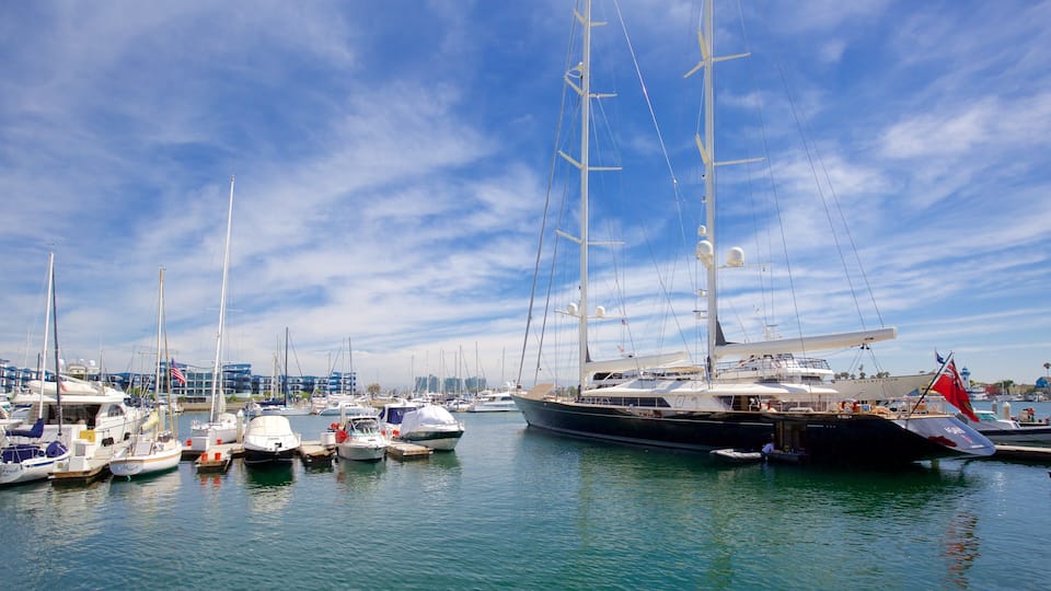 A marina with various sailboats docked, a large yacht, and a clear blue sky.