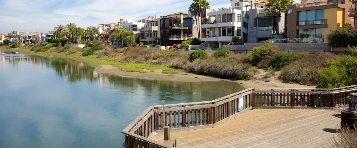 A waterfront with modern buildings, a wooden dock, and a calm river.