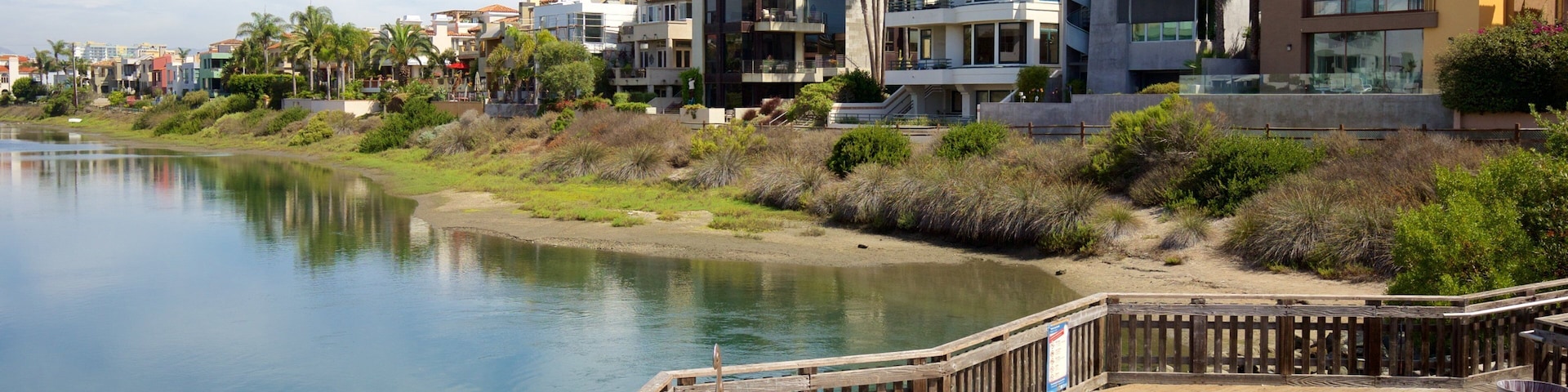 A waterfront with modern buildings, a wooden dock, and a calm river.
