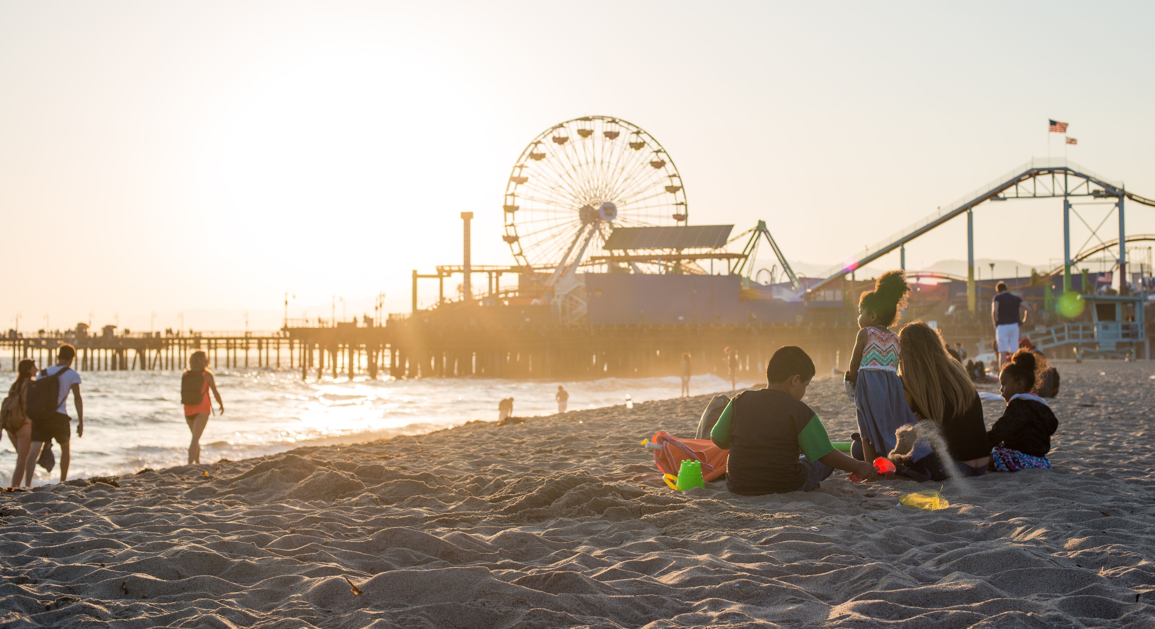 A beach with a Ferris wheel and a roller coaster in the background.