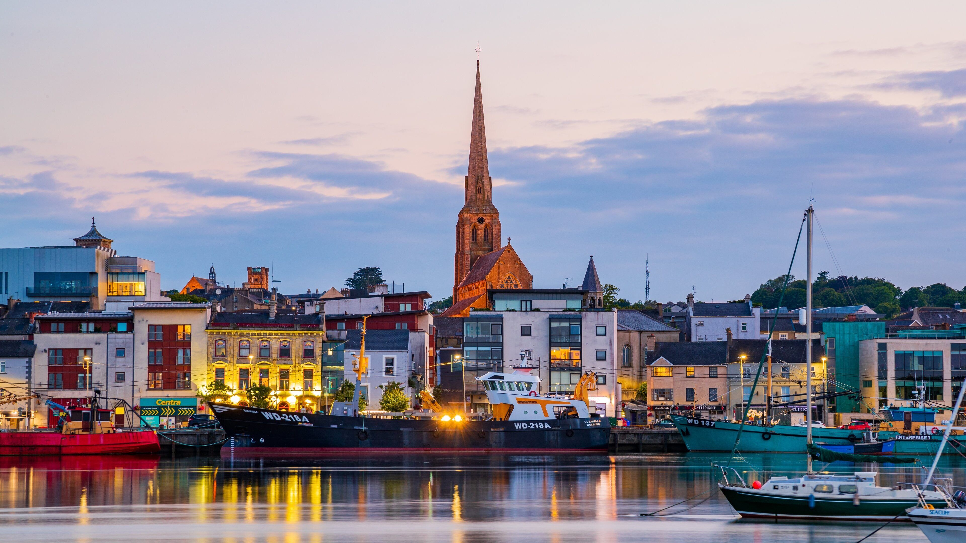 A harbor with boats, a church spire, and buildings.