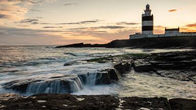 Un faro en una costa rocosa, con olas rompiendo contra las rocas.