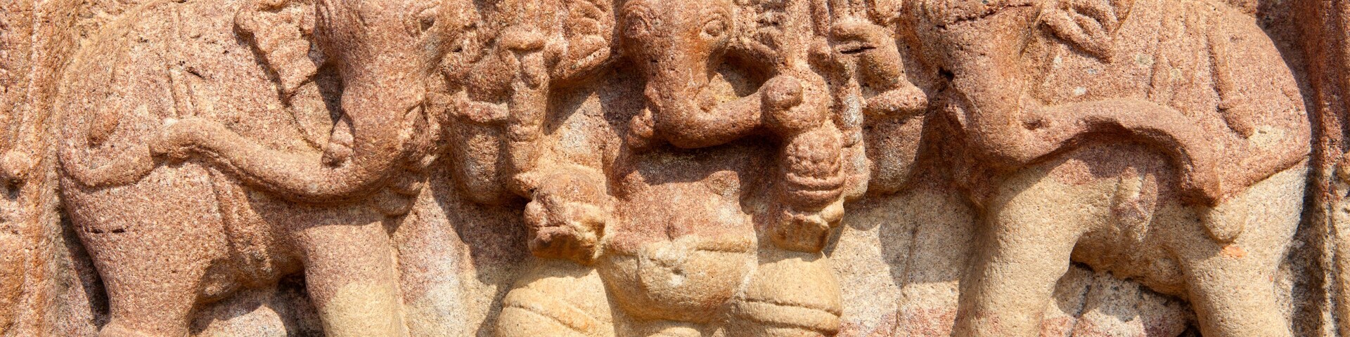 Une sculpture en grès représentant une divinité à plusieurs bras, entourée d’éléphants.