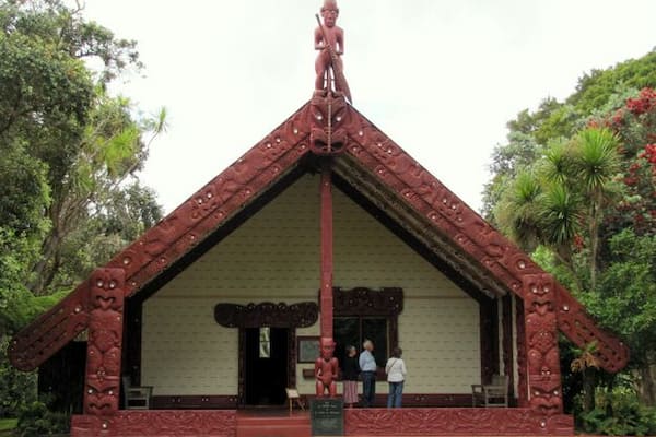 A red-roofed building with intricate carvings and a statue on top.