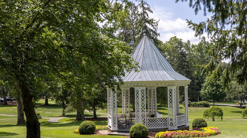 A gazebo in a park surrounded by trees and well-maintained lawns.