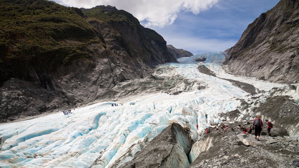 A glacier with people hiking on its surface.