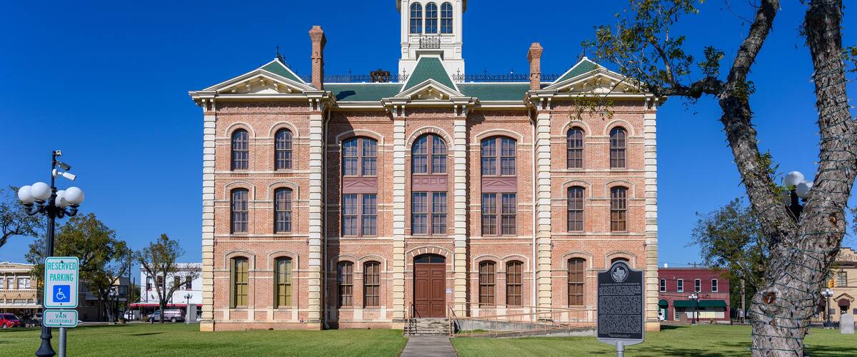A historic brick building with a clock tower, green roof, and a central entrance.