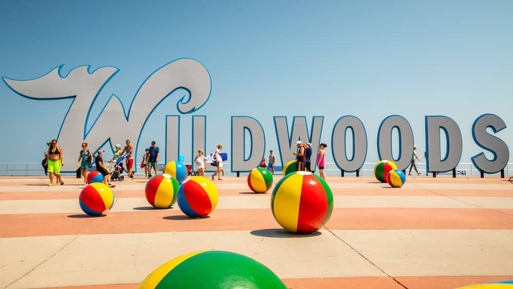 A beach with large letters spelling "WILDWOOODS" and colorful beach balls.