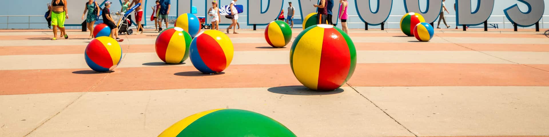 A beach with large letters spelling "WILDWOOODS" and colorful beach balls.