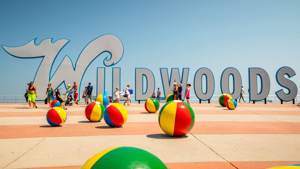 A beach with large letters spelling "WILDWOOODS" and colorful beach balls.