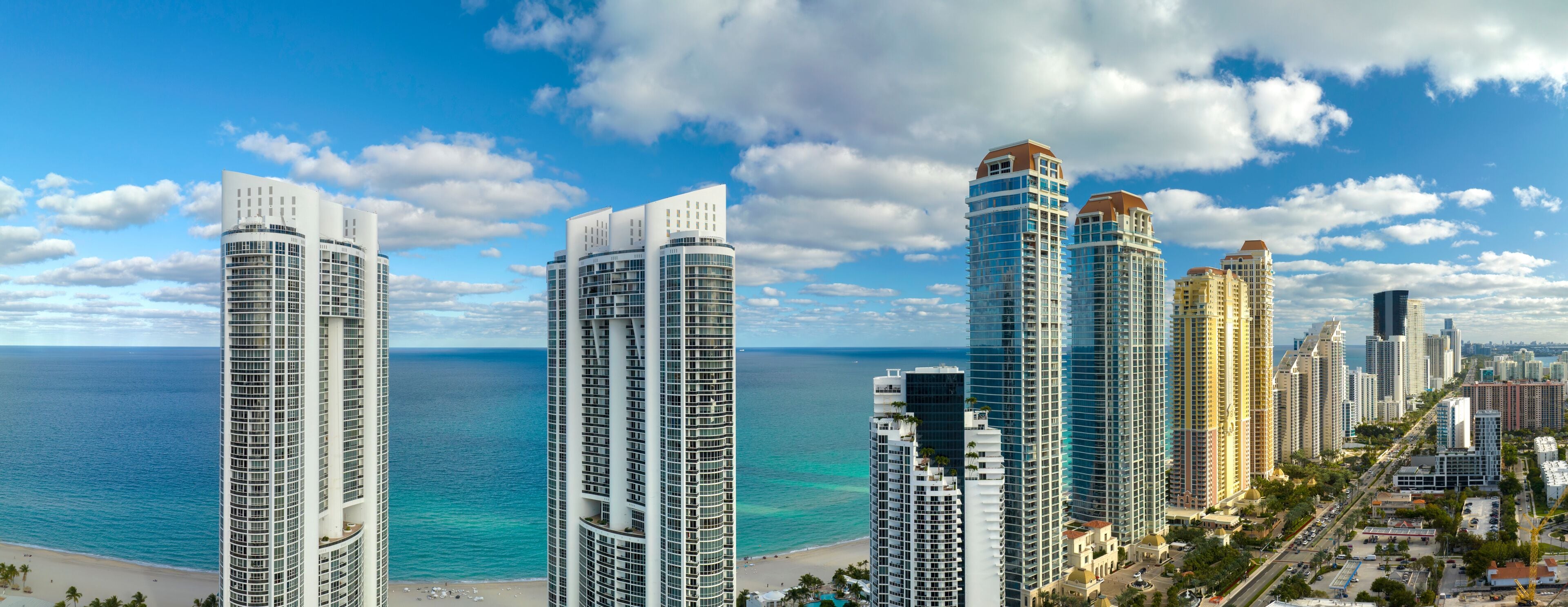 Aerial view of Sunny Isles Beach city with luxurious highrise hotels and condos on Atlantic ocean shore. American tourism infrastructure in southern Florida