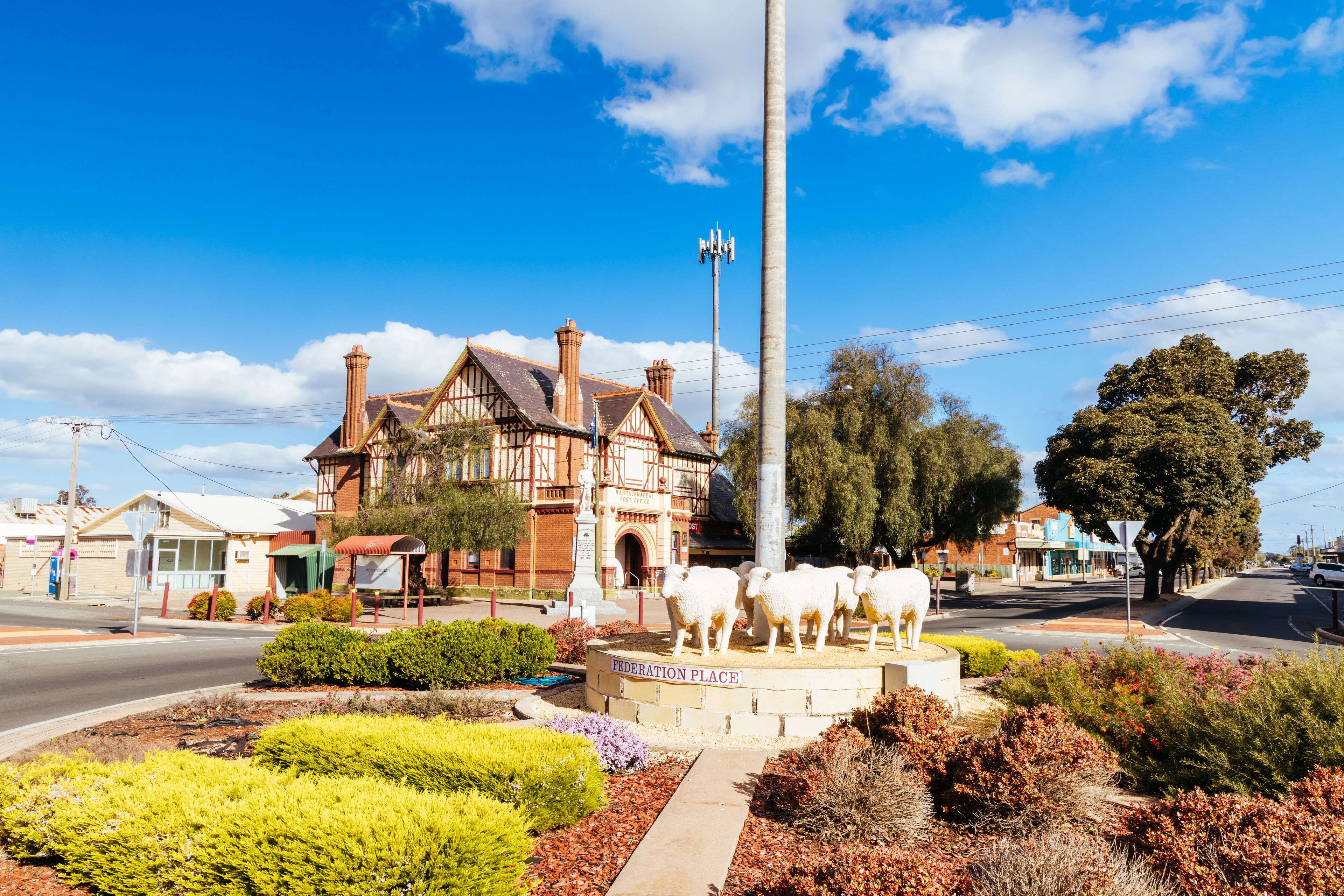 Federation Place with a statue of sheep, a large building, and surrounding greenery.