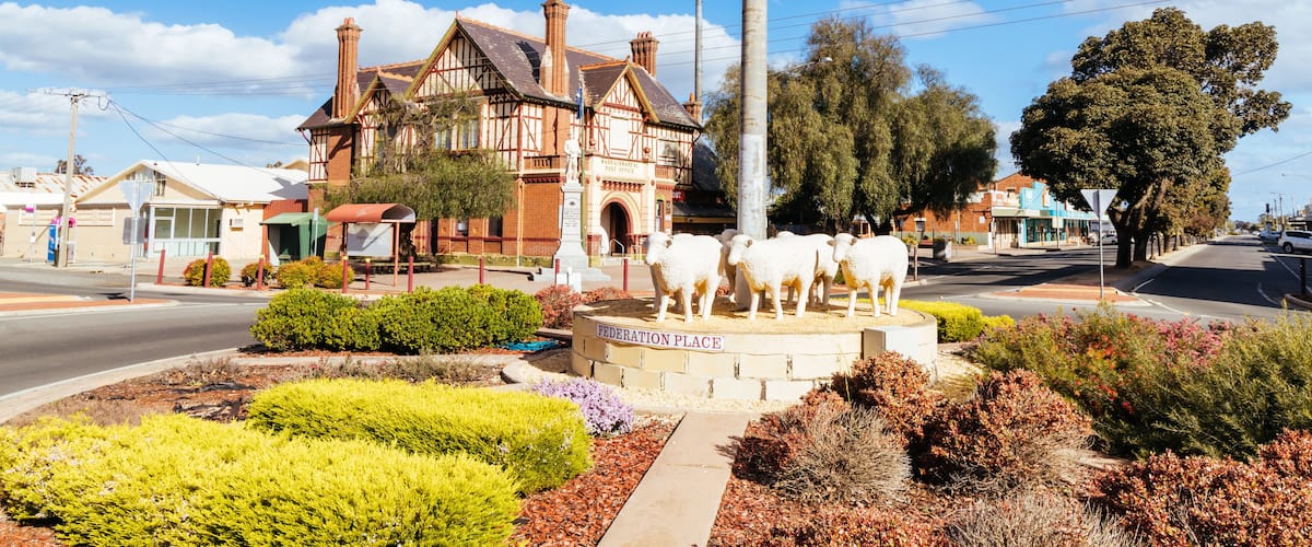 Federation Place with a statue of sheep, a large building, and surrounding greenery.