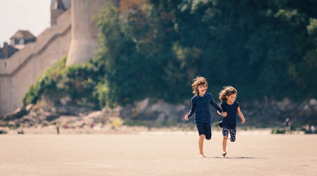 Young sisters running on the beach in front of Mont Saint Michel
