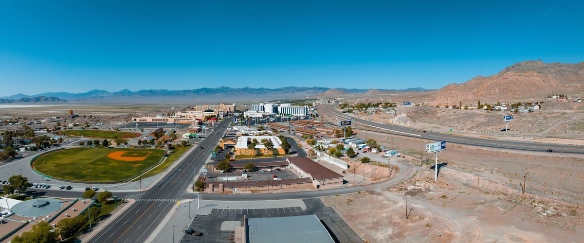 A town with a baseball field, roads, buildings, and mountains in the background.