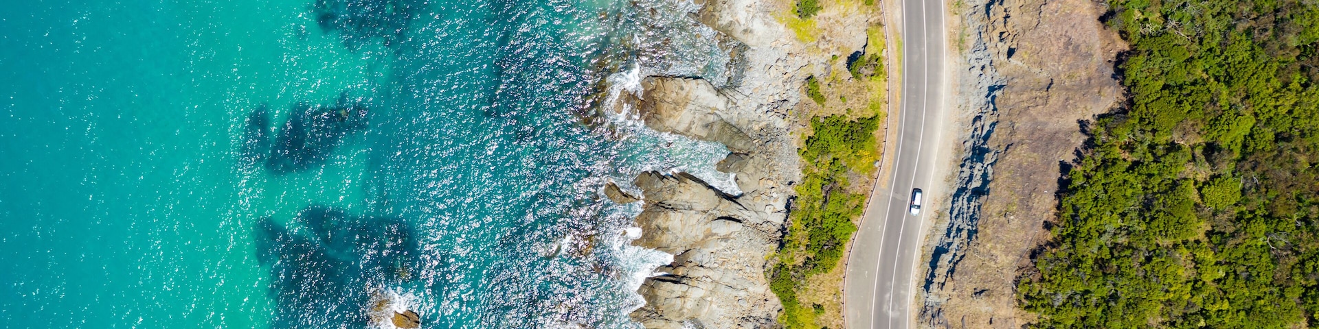 Una carretera costera con acantilados y un mar turquesa.
