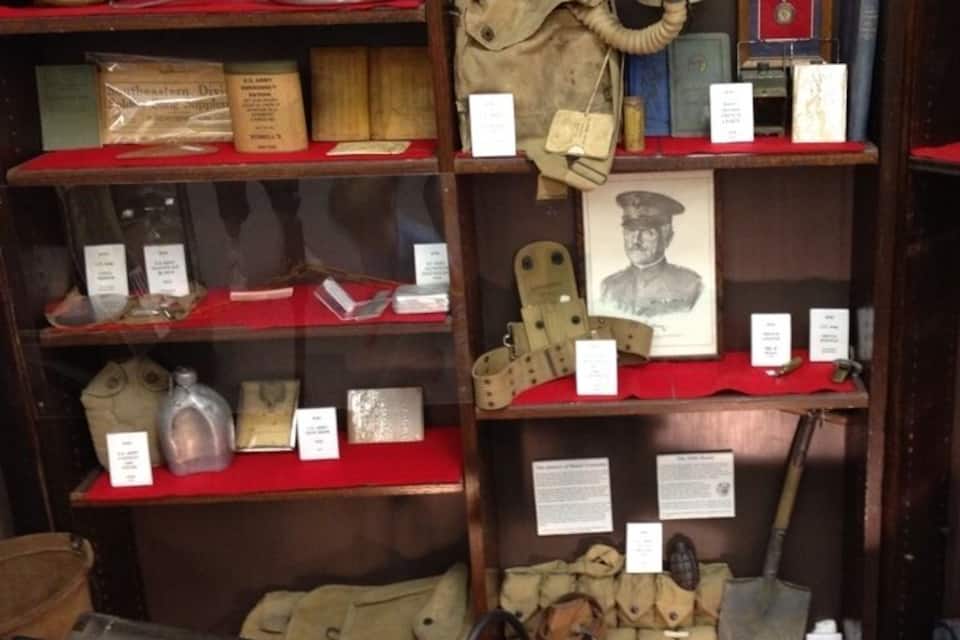 A museum display with military artifacts including a gas mask, a rifle, and various personal items.