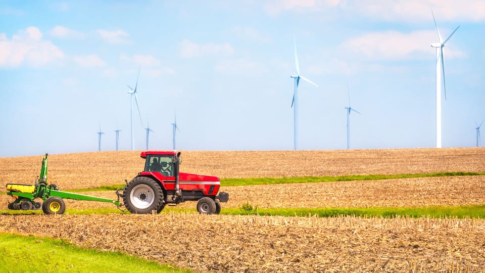 USA farmer farming with tractor on wind farm Danville Illinois