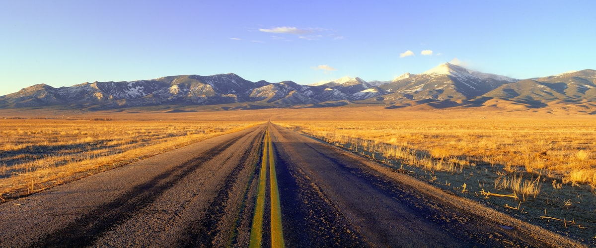 A road leading to snow-capped mountains.