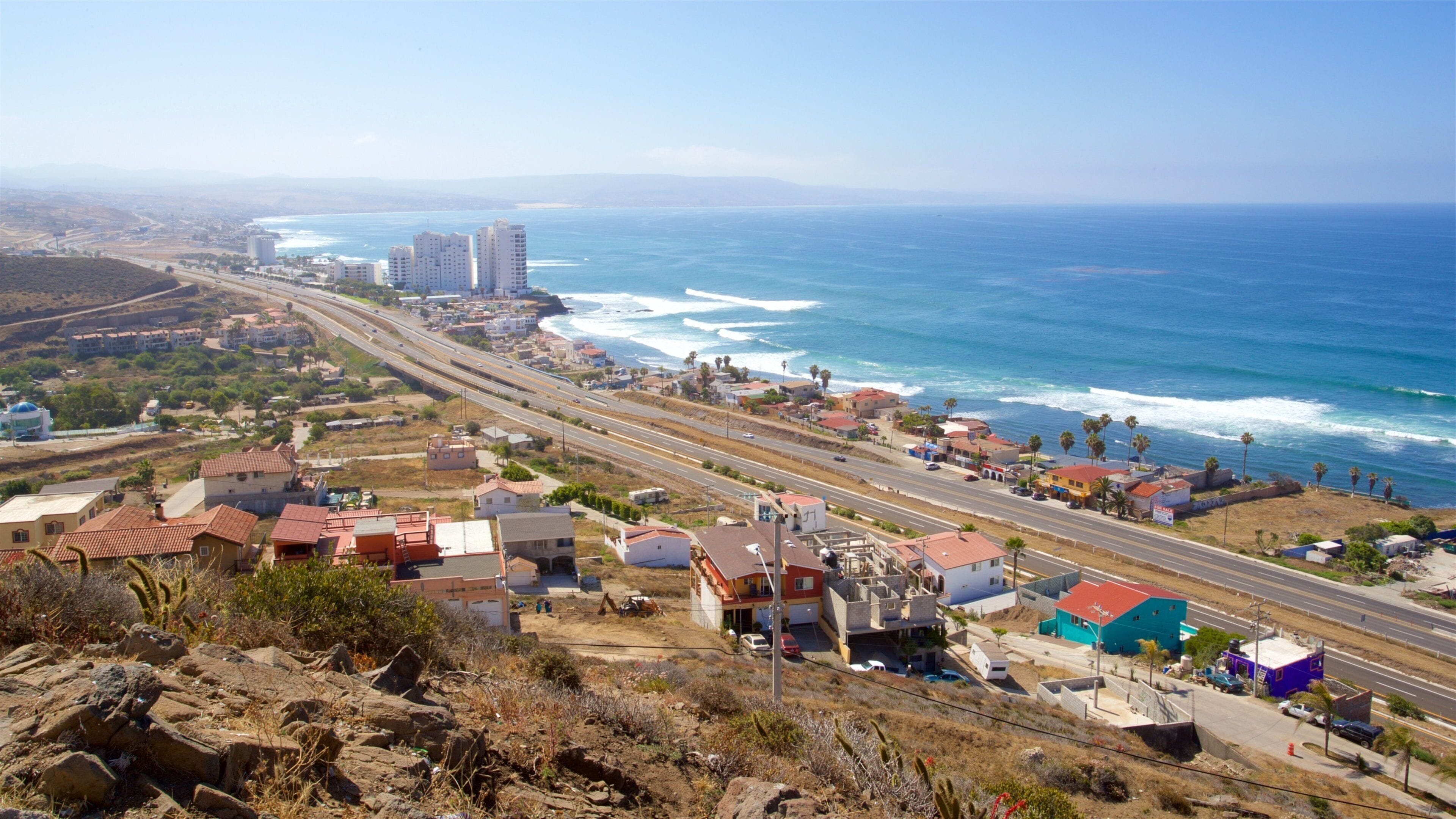 A coastal town with a highway, buildings, and the ocean.
