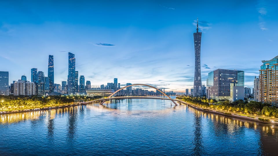 A city skyline with a prominent tower, a bridge over a river, and illuminated buildings.