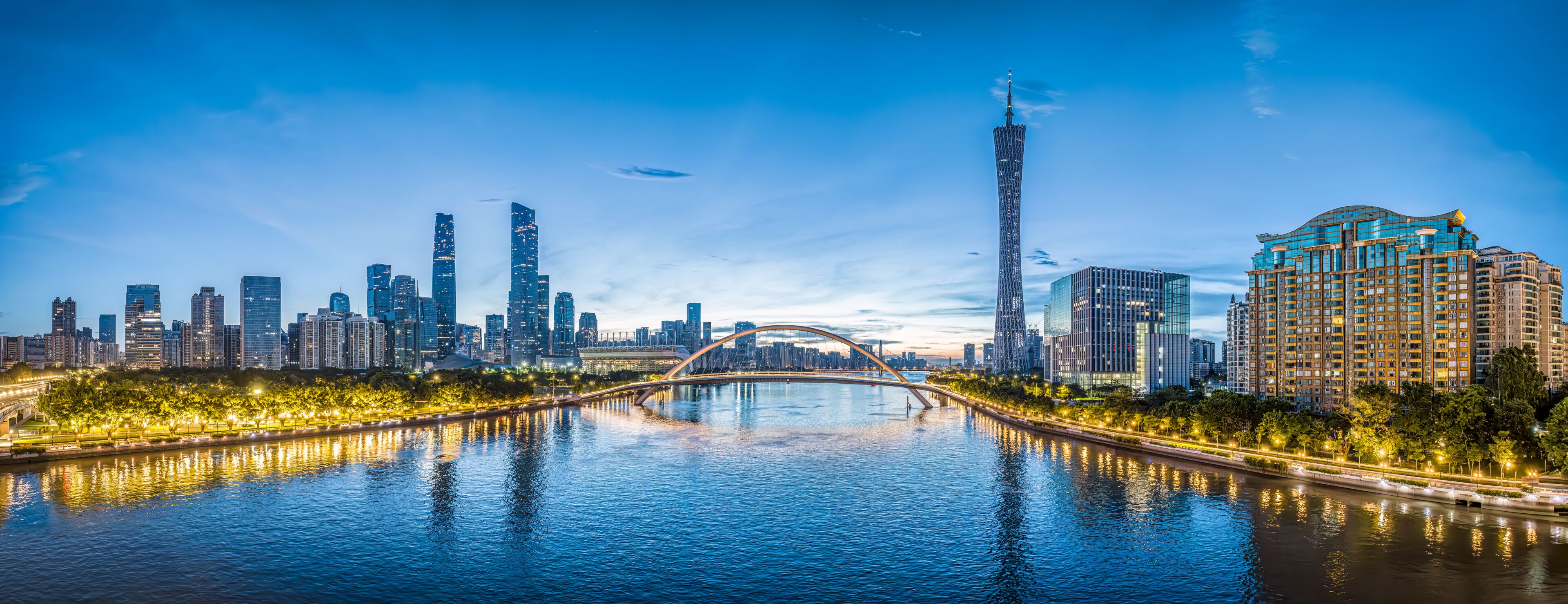 A city skyline with a prominent tower, a bridge over a river, and illuminated buildings.