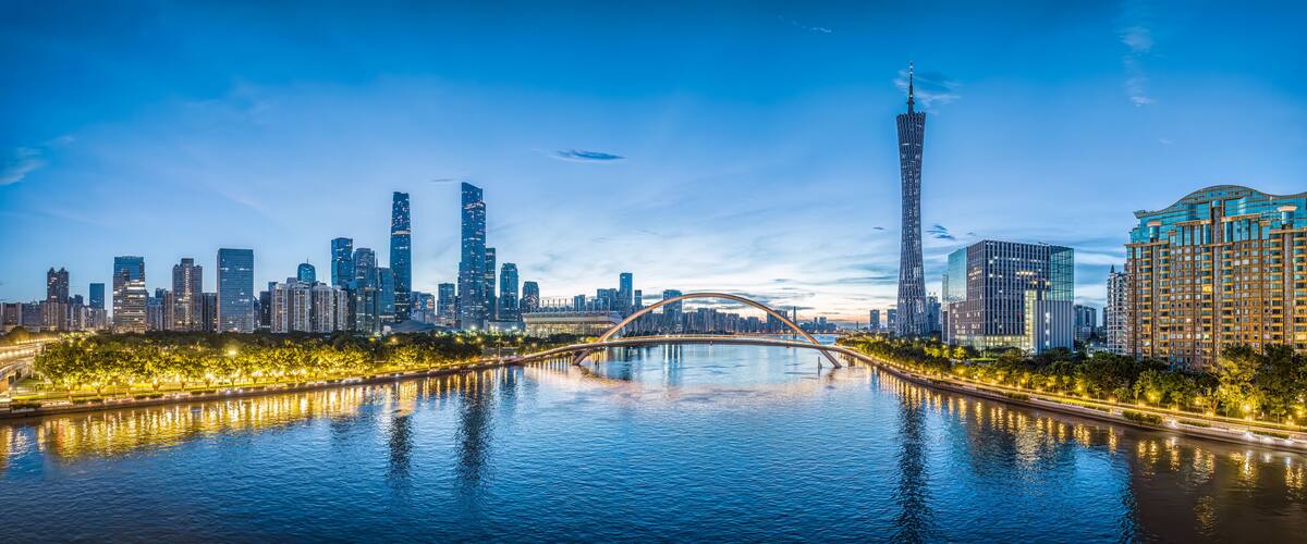 A city skyline with a prominent tower, a bridge over a river, and illuminated buildings.