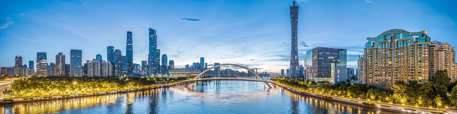 A city skyline with a prominent tower, a bridge over a river, and illuminated buildings.