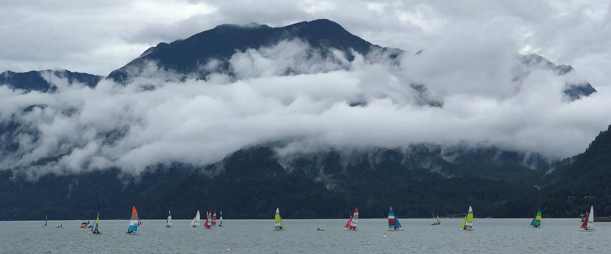 A lake with sailboats and mountains in the background.
