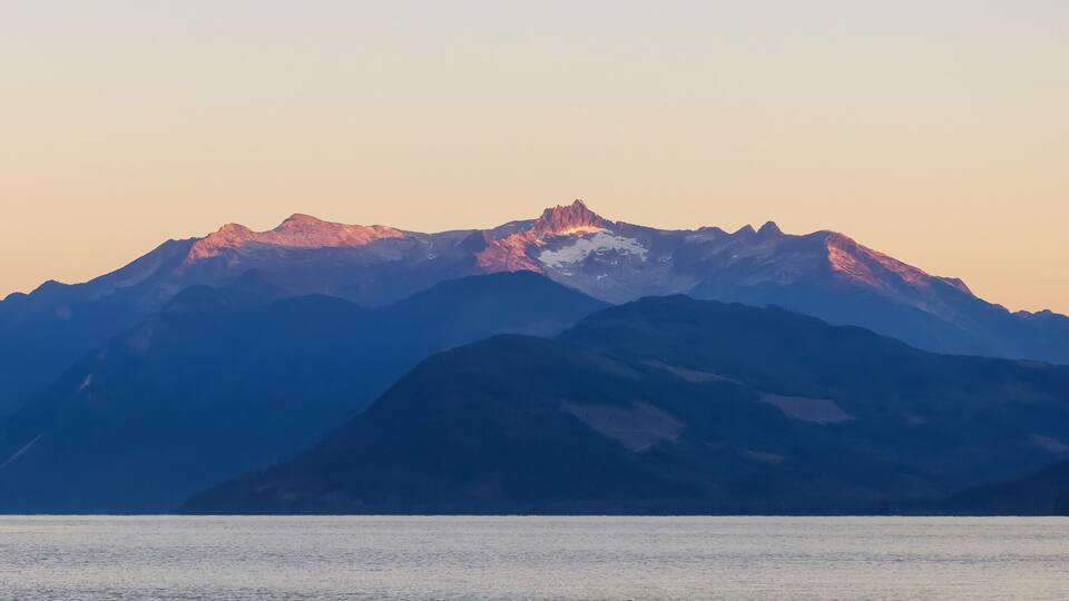 A mountain range with a lake in the foreground.